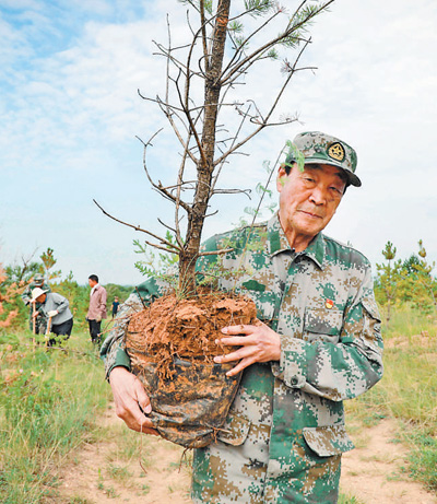 　　张连印在山西左云县张家场乡北梁山坡种树时搬运树苗。丁美宁摄（新华社发）
