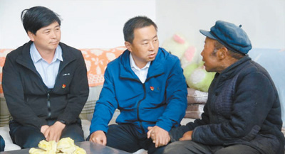 王宝林（中）走访贫困户。资料照片
